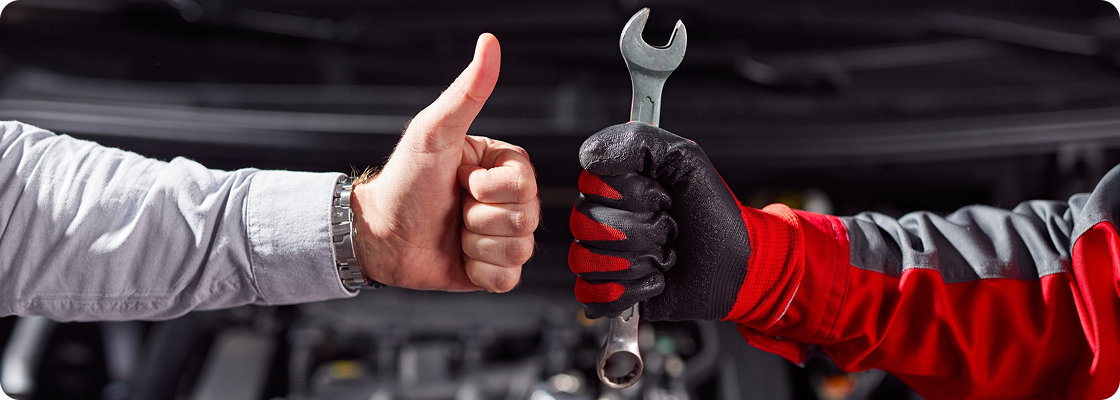 Automechaniker gibt Daumen hoch mit Schraubenschlüssel